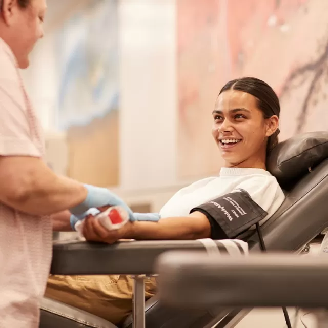 photo of a woman seated in a donation chair smiling at a nurse in front of her