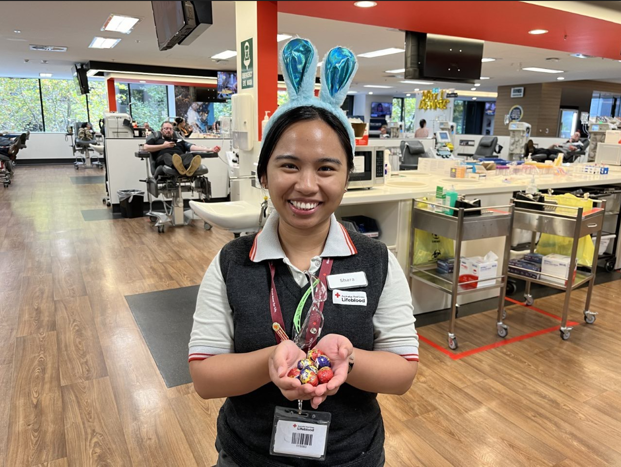 Donor centre staff member wearing bunny ears and holding easter eggs